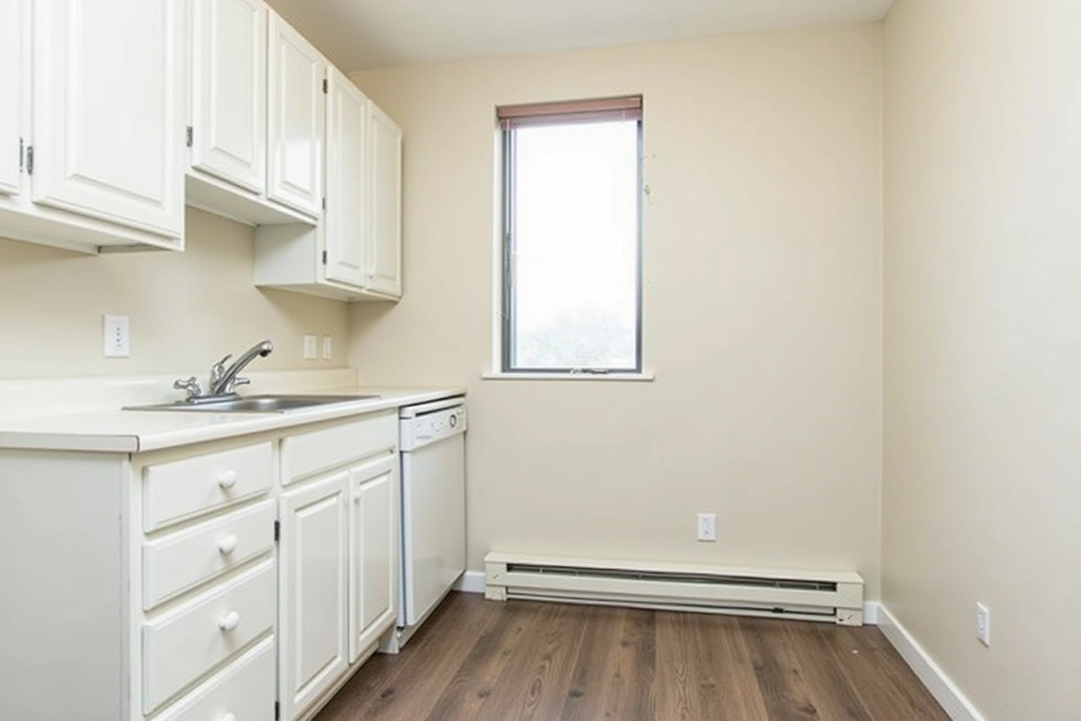 Small rental kitchen with white raised-panel stock cabinets, a laminate counter, a white dishwasher and one window.