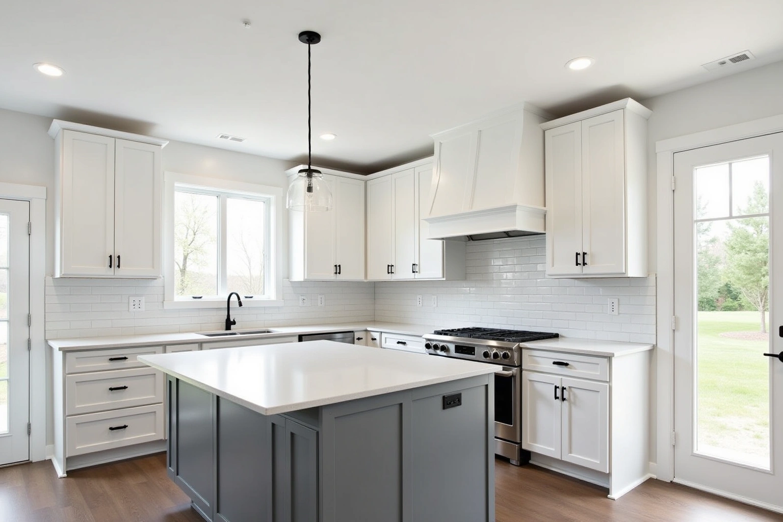 White shaker kitchen cabinets with black pulls, a grey island, white subway tile and a white range hood.
