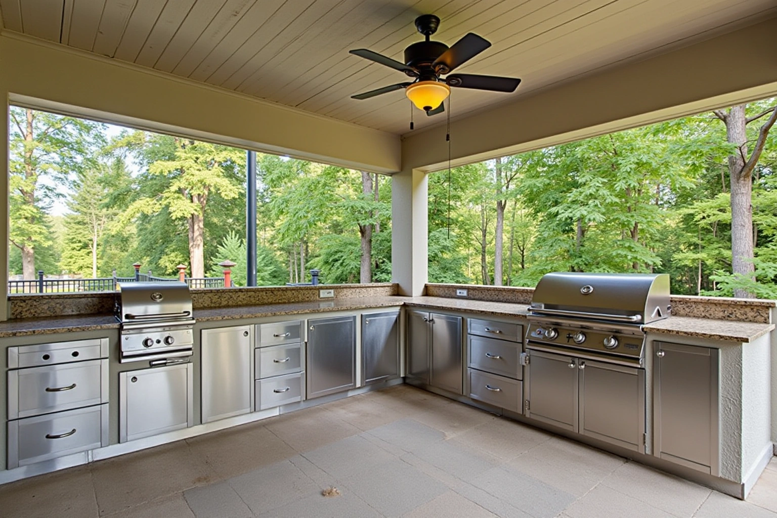 Covered patio kitchen with stainless steel cabinets and drawers under granite counters, a built-in grill and a ceiling fan.